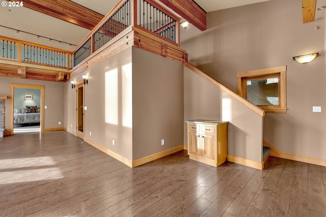 interior space with beamed ceiling, hardwood / wood-style floors, and a towering ceiling