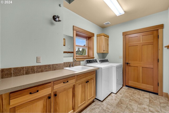 washroom featuring sink, cabinets, and independent washer and dryer