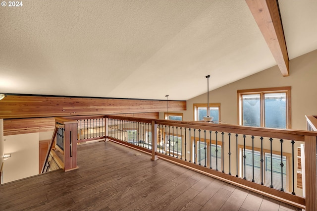 corridor with wood-type flooring, lofted ceiling with beams, and a textured ceiling