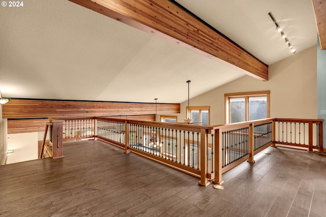 corridor featuring rail lighting, vaulted ceiling with beams, and dark wood-type flooring