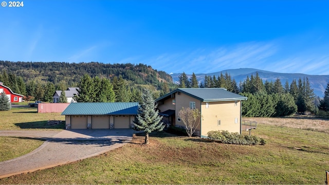 exterior space featuring a mountain view, a garage, and a front lawn