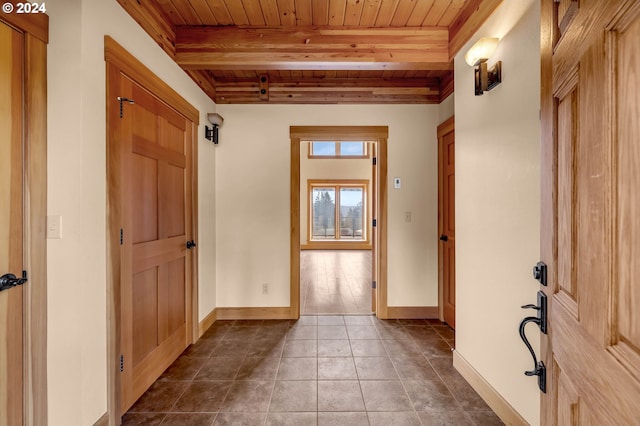 entryway featuring beamed ceiling, dark tile patterned floors, and wood ceiling