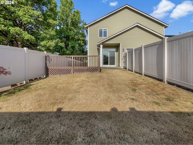 rear view of property featuring a yard and a wooden deck