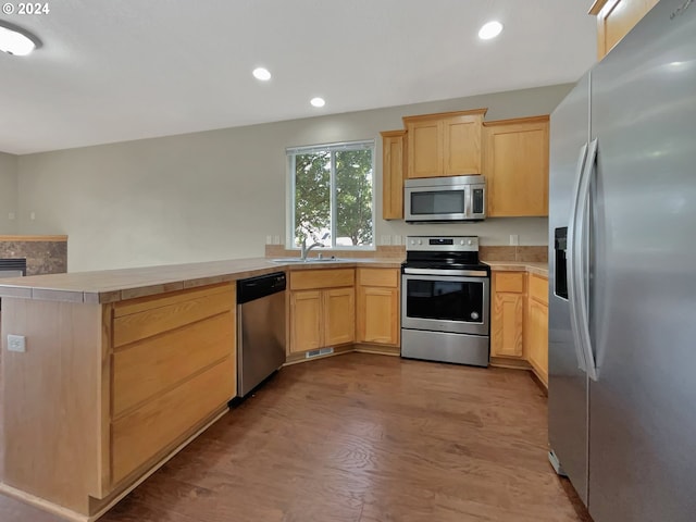 kitchen featuring kitchen peninsula, stainless steel appliances, light hardwood / wood-style floors, light brown cabinets, and sink