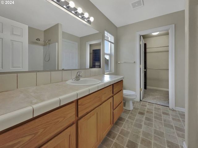 bathroom featuring a shower, vanity, and toilet