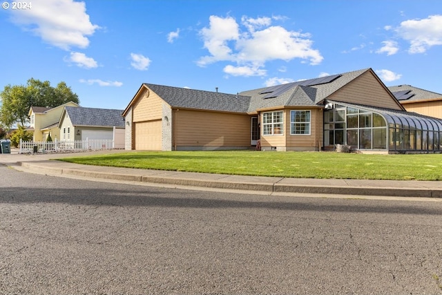 view of front of home with a garage, solar panels, and a front lawn