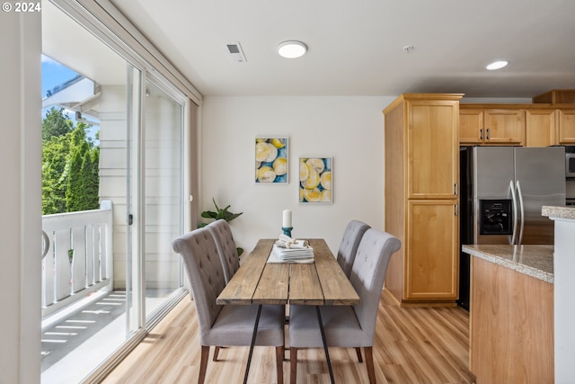 kitchen with light stone counters, stainless steel fridge, and light hardwood / wood-style floors