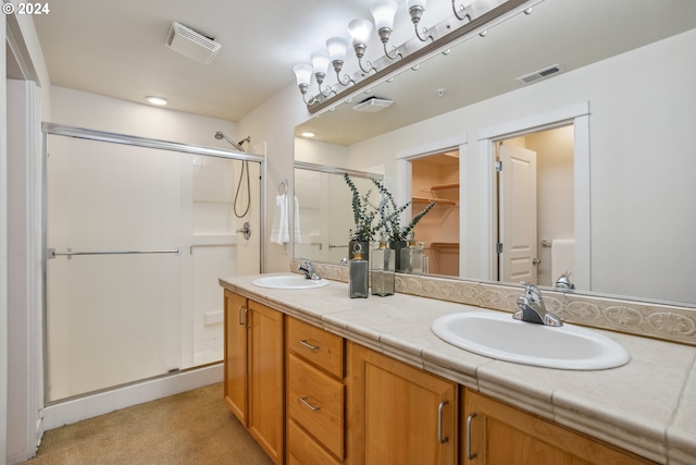 bathroom featuring dual vanity and a shower with shower door