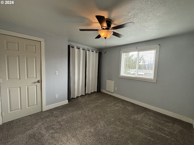 unfurnished bedroom with dark colored carpet, ceiling fan, and a textured ceiling