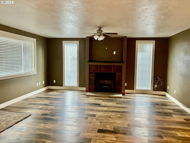 unfurnished living room featuring hardwood / wood-style floors, ceiling fan, and a tiled fireplace