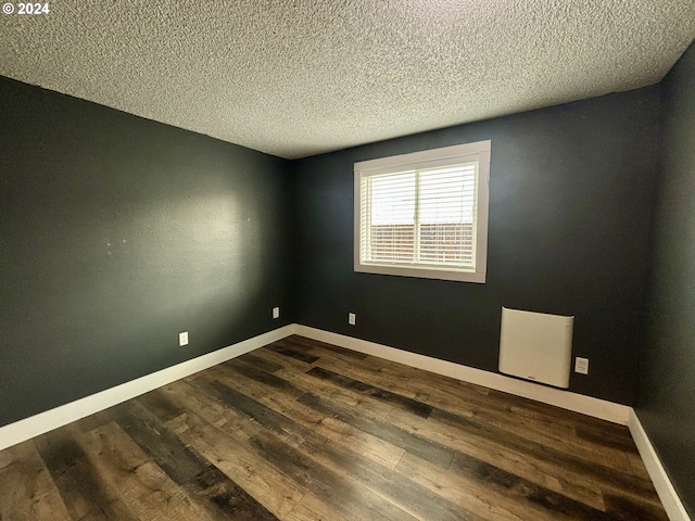 empty room with a textured ceiling, radiator, and dark hardwood / wood-style floors