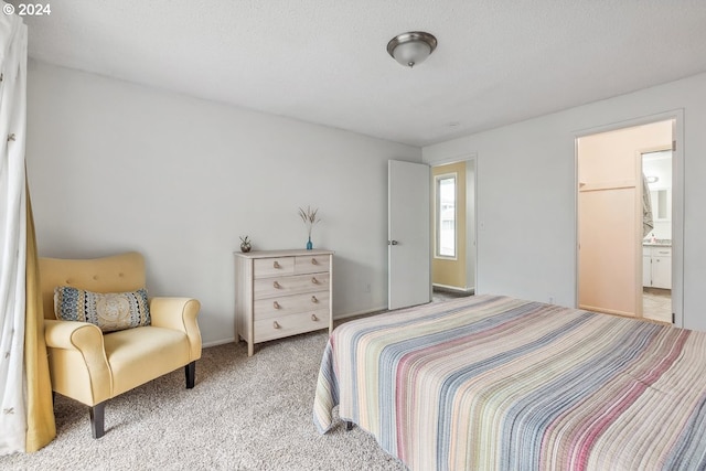 carpeted bedroom with a textured ceiling and ensuite bath