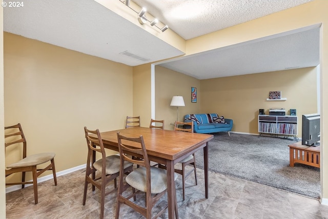 dining area with light colored carpet and a textured ceiling