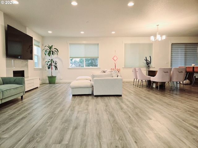 living room featuring light wood-type flooring, a fireplace, and an inviting chandelier