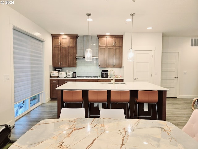 kitchen with dark wood-type flooring, sink, hanging light fixtures, and gas cooktop