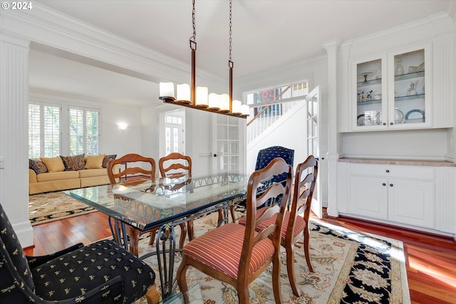 dining area featuring wood-type flooring, ornamental molding, and an inviting chandelier