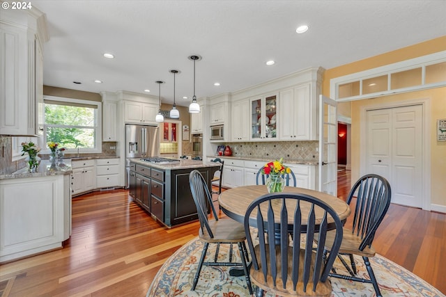 kitchen with a kitchen island, stainless steel appliances, a wealth of natural light, and light hardwood / wood-style flooring