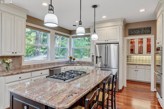 kitchen with white cabinets, decorative backsplash, a center island, and stainless steel appliances