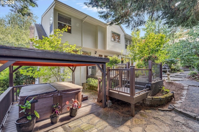 back of property featuring a gazebo, a wooden deck, and a hot tub