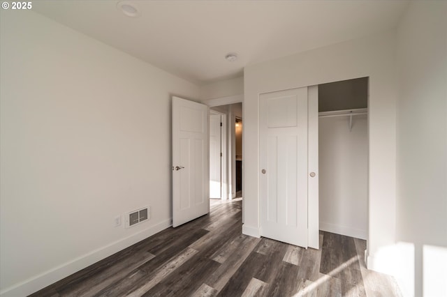 unfurnished bedroom featuring a closet and dark hardwood / wood-style floors