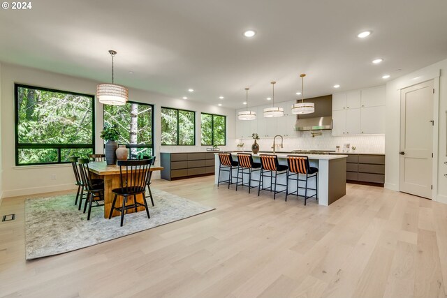 kitchen featuring white cabinets, pendant lighting, a healthy amount of sunlight, and a large island with sink