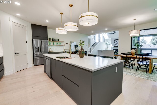 kitchen featuring light hardwood / wood-style floors, a kitchen island with sink, sink, and appliances with stainless steel finishes