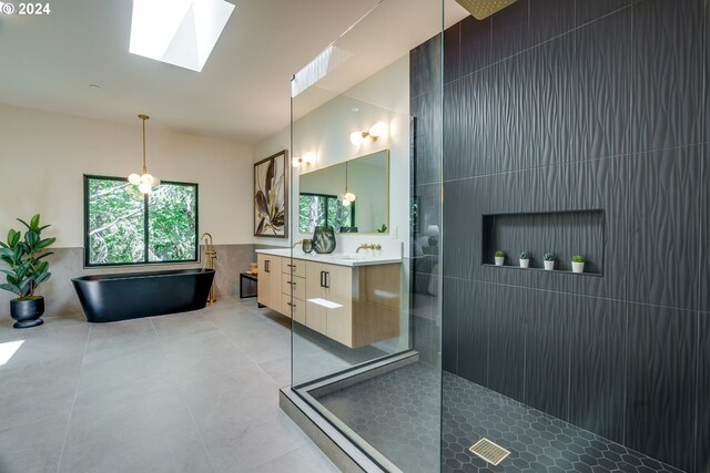 bathroom with a skylight, plus walk in shower, vanity, and tile walls