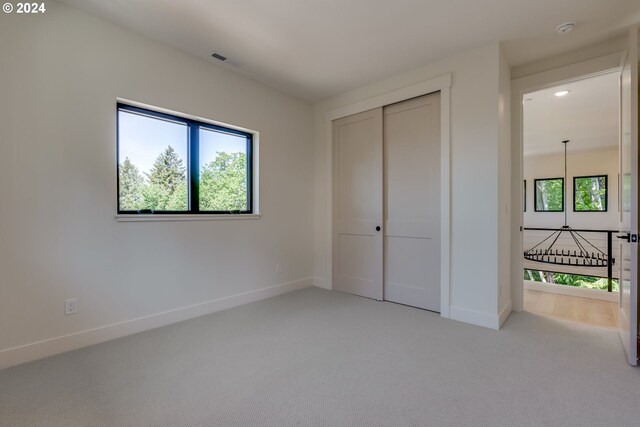 unfurnished bedroom with light carpet and a closet