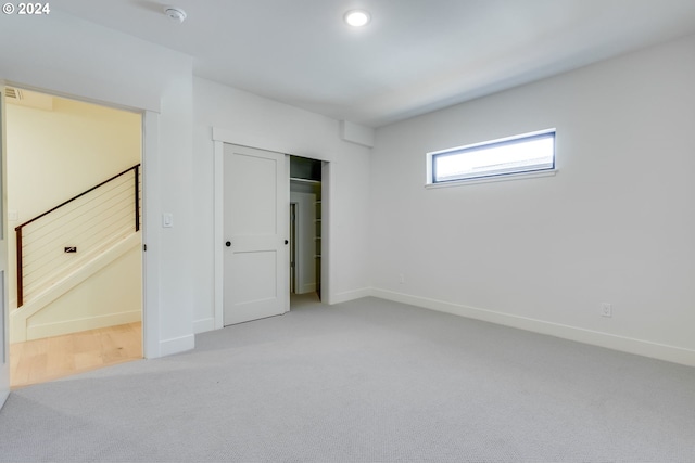 unfurnished bedroom featuring light carpet and a closet