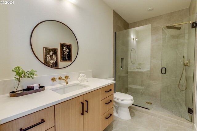 bathroom with tile patterned floors, vanity, toilet, and walk in shower