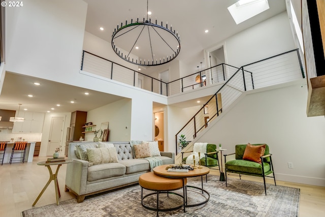 living room with a towering ceiling, light hardwood / wood-style floors, and an inviting chandelier