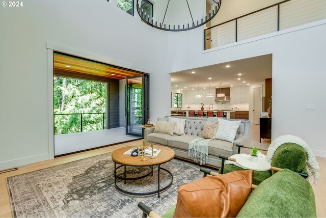 living room with hardwood / wood-style floors, a notable chandelier, a towering ceiling, and sink