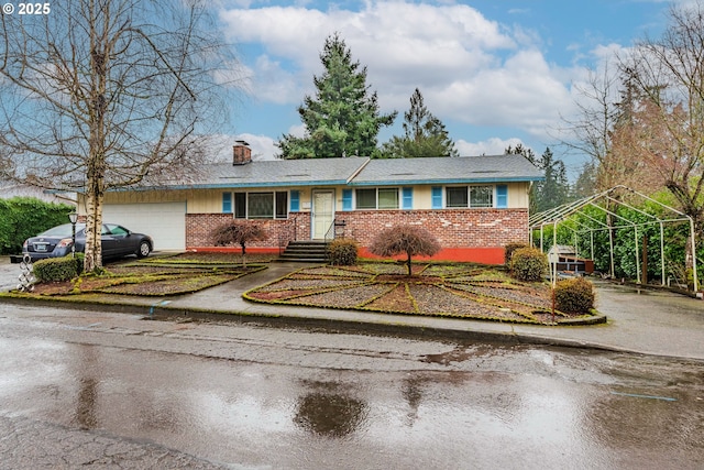 view of front of house with a garage, driveway, a chimney, and brick siding