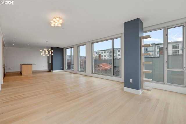 unfurnished living room with an inviting chandelier, light wood-type flooring, and a healthy amount of sunlight