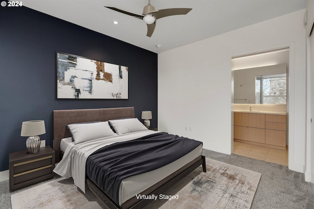 bedroom featuring light carpet, sink, ensuite bathroom, and ceiling fan