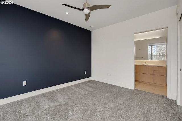 unfurnished bedroom featuring ceiling fan, ensuite bath, light carpet, and sink