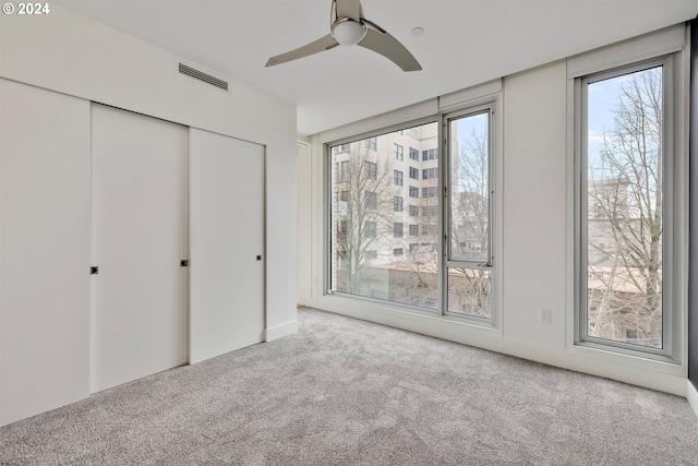 unfurnished bedroom featuring light carpet, a closet, and ceiling fan