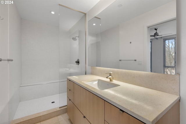 bathroom featuring ceiling fan, vanity, a tile shower, and tile patterned floors