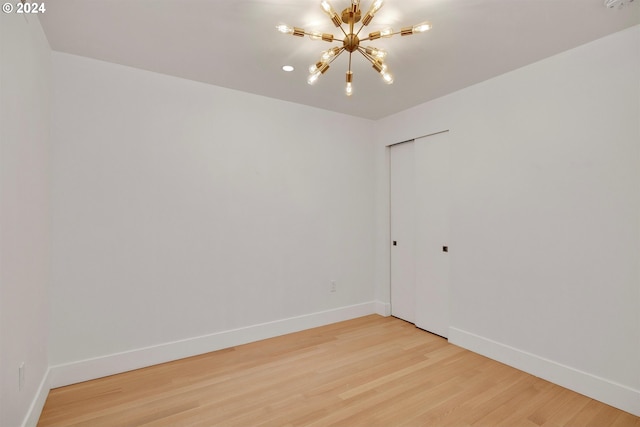 empty room with hardwood / wood-style flooring and a chandelier