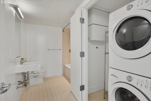 washroom with sink, light tile patterned floors, and stacked washer and clothes dryer