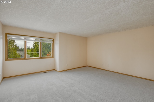 empty room with a textured ceiling and light colored carpet