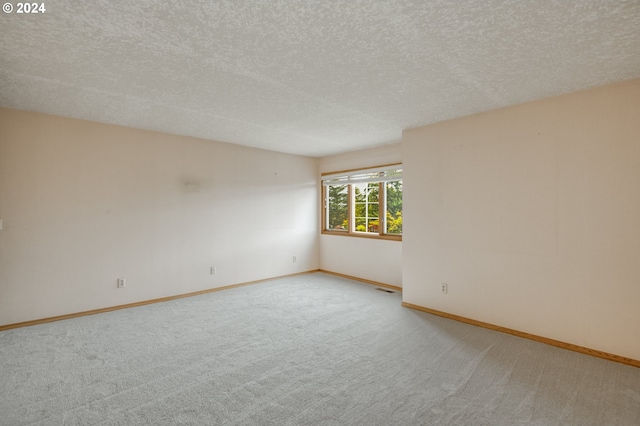 carpeted empty room featuring a textured ceiling