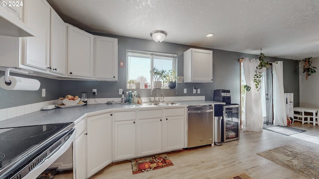 kitchen with stainless steel dishwasher, sink, light hardwood / wood-style floors, white cabinetry, and a textured ceiling