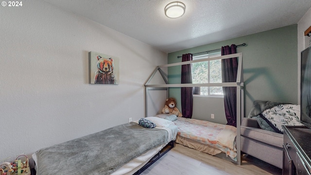 bedroom with hardwood / wood-style flooring and a textured ceiling