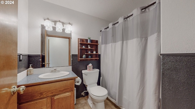 bathroom featuring tile patterned flooring, curtained shower, vanity, and toilet