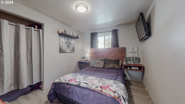 bedroom with light wood-type flooring and a textured ceiling