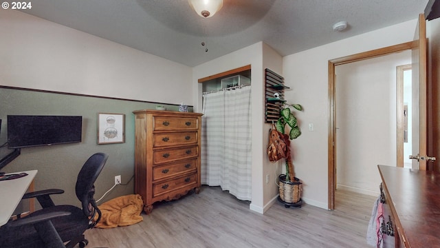 home office with light hardwood / wood-style floors and a textured ceiling