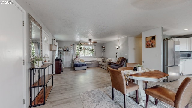 dining space with ceiling fan, light hardwood / wood-style floors, and a textured ceiling