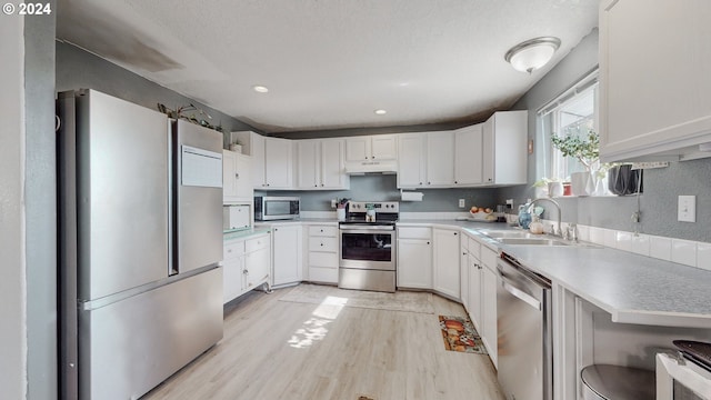 kitchen with white cabinets, light hardwood / wood-style floors, appliances with stainless steel finishes, and sink