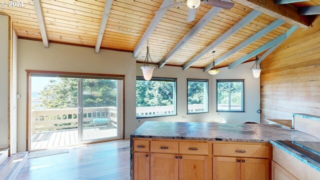 kitchen featuring pendant lighting, lofted ceiling with beams, light wood-type flooring, and wooden walls